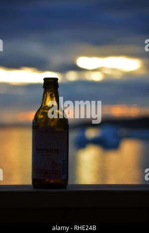 Ilulissat, Groenland - 4 juillet 2016 - profiter du soleil de minuit et de la vue dans la baie disco avec une bouteille de bière groenlandaise - Immiaraq Lager Banque D'Images