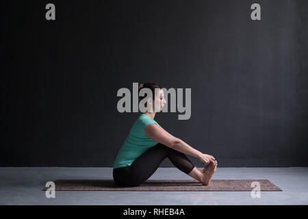 Woman practicing yoga, faire assis flexion avant pose, à l'aide de mains. Banque D'Images