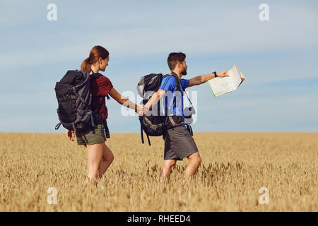 Un couple de voyageurs avec des sacs à dos, rendez-vous sur une route. Banque D'Images