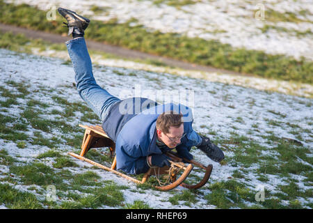 Un homme de la luge dans le parc de Greenwich, dans le sud de Londres, après une nuit de neige hier et devraient entraîner des troubles. Banque D'Images