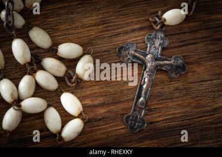 Croix catholique avec un rosaire sur un fond de bois Banque D'Images