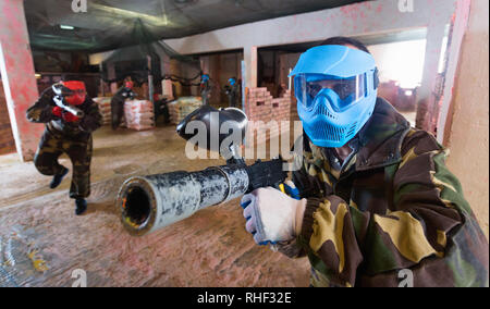 Portrait de l'équipe bleu heureux joueur qui est positif visant en adversaires sur le terrain de paintball.