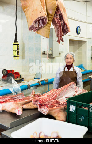 Portrait de femmes qualifiés worker cutting la viande crue dans l'usine de conditionnement des viandes Banque D'Images