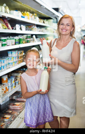 Une femme heureuse et cute girl picking produits laitiers frais dans la section réfrigérée dans l'épicerie Banque D'Images