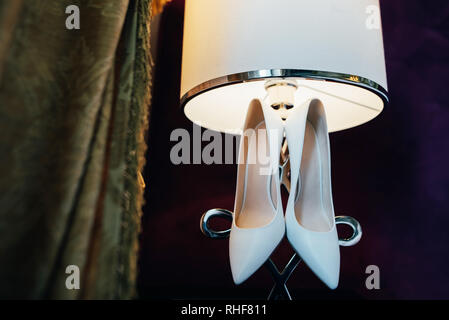 Pour la mariée chaussures couple accroché à la lampe à l'hôtel. Banque D'Images