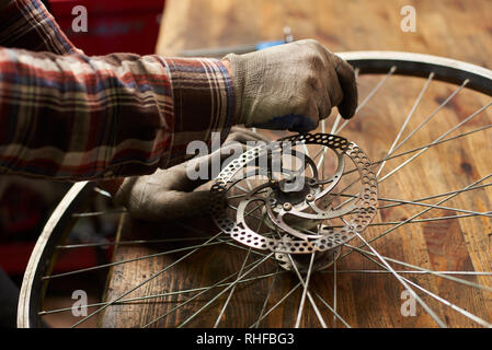 Portrait de femme en travail mécanique atelier de réparation de vélos, la réparation de roues de vélo militaire à l'aide de l'outil, en portant des vêtements et des gants Banque D'Images