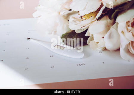 Calendrier d'Ovulation avec de faux pivoine rose et thermomètre Banque D'Images