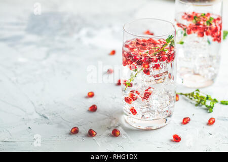 Boissons de fête, gin tonic cocktail de grenade ou de l'eau avec de la glace. detox Focus sélectif, l'espace de copie de texte, de la surface de la table en béton gris clair. Banque D'Images