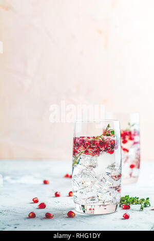 Boissons de fête, gin tonic cocktail de grenade ou de l'eau avec de la glace. detox Focus sélectif, l'espace de copie de texte, de la surface de la table en béton gris clair. Banque D'Images