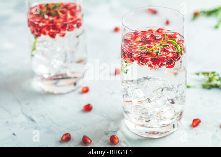 Boissons de fête, gin tonic cocktail de grenade ou de l'eau avec de la glace. detox Focus sélectif, l'espace de copie de texte, de la surface de la table en béton gris clair. Banque D'Images