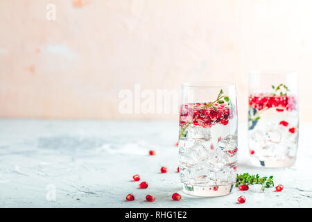 Boissons de fête, gin tonic cocktail de grenade ou de l'eau avec de la glace. detox Focus sélectif, l'espace de copie de texte, de la surface de la table en béton gris clair. Banque D'Images