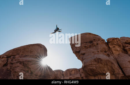 Défi, le risque et la liberté concept. Une Silhouette man jumping over précipice crossing cliff Banque D'Images