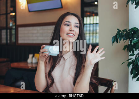 Belle charmante brunette longs cheveux smiling asian girl a petit-déjeuner avec café au café et forme à des amis Banque D'Images