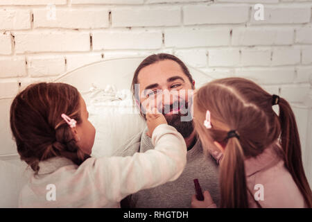 Belle filles mignonnes appliquer le rouge à lèvres sur leur papa Banque D'Images