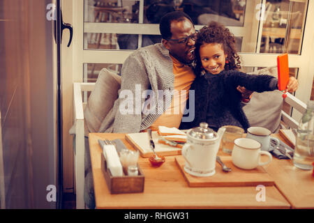 Cute daughter holding her smartphone faire photo avec père Banque D'Images