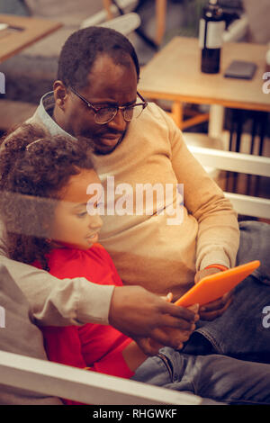 Père portant des lunettes serrant ses petite princesse regarder cartoon Banque D'Images