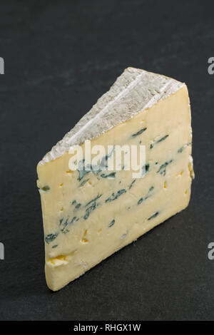 Un morceau de fromage en provenance d'Affine Montagnolo Bavière, Allemagne fabriqué à partir de lait de vache, photographié sur un fond foncé, ardoise. England UK GO Banque D'Images