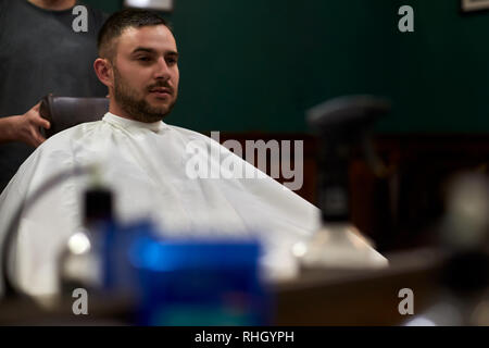 Reflet d'un salon de la main. Barbu hippie client obtient hair in front of mirror Banque D'Images