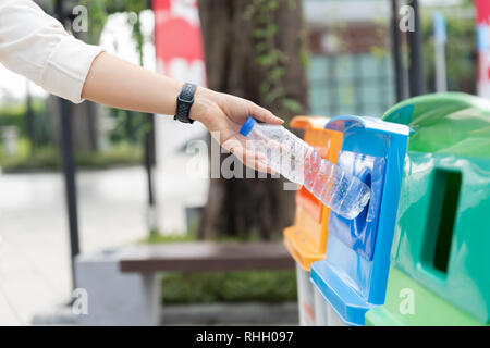 Closeup portrait woman throwing vide bouteille d'eau en plastique dans le bac de recyclage. Banque D'Images
