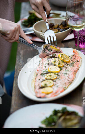 Le saumon avec du citron mains servant d'argent avec la fourchette du plateau. Banque D'Images