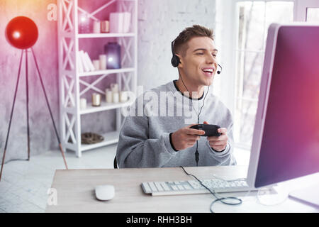 Handsome student moderne friands de jeux vidéo tout en jouant joyeuse sensation Banque D'Images