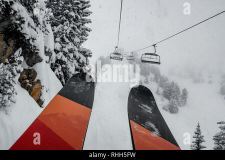 Télésiège de ski skieurs et planchistes portant jusqu'à la montagne pendant les fortes chutes de neige sur une journée d'hiver brumeux à Courchevel, France. Banque D'Images