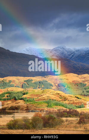 Un arc-en-ciel sur le Loch avec Tromlee Crauchan un Ben enneigées au loin. Banque D'Images