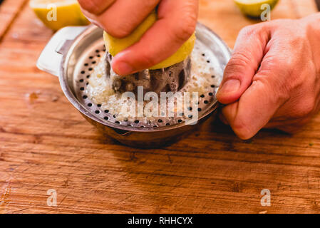 Les mains serrant le jus d'un citron. Banque D'Images
