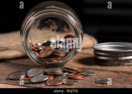Pot mason de verre avec quelques pièces de monnaie à l'intérieur pour illustrer la pauvreté Banque D'Images