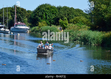 Les gens sur une petite embarcation à moteur se déplaçant le long de la rivière Frome à Wareham, Dorset, UK. Rivière avec bateaux disponibles à l'arrière-plan. Banque D'Images