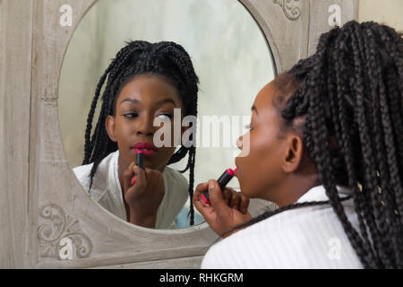 Pretty young african american woman doing her routine du matin devant le miroir de salle de bains Banque D'Images