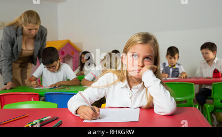 Portrait de l'écolière ennuyé assis en classe avec leurs camarades et l'enseignant Banque D'Images