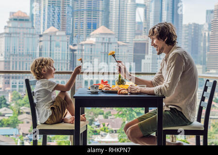 Famille heureuse de prendre le petit déjeuner sur le balcon. Table de petit-déjeuner avec café et fruits pain croisant sur un balcon dans le contexte de la grande ville Banque D'Images