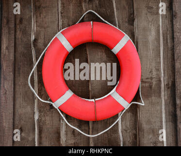 Bouée ronde rouge et accroché sur un mur en bois brun. Partie de bouée couverte de neige Banque D'Images