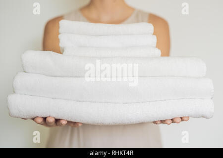 Une femme tient une pile de serviettes blanches. Concept de service dans les hôtels, blanchisserie, spa Banque D'Images