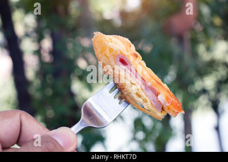 Croissant jambon avec fourchette dans le contexte de la nature verte. Banque D'Images
