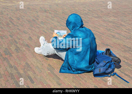 Teenage boy in blue Jacket le dessin en dehors sur la rue Banque D'Images