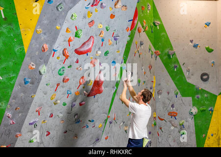 Climber explore et développe un itinéraire sur un mur d'escalade dans la salle de blocs Banque D'Images