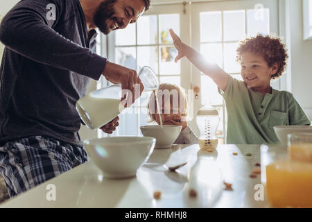 Père ce qui fait du petit déjeuner pour ses enfants à la maison. L'homme s'amusant préparer le petit-déjeuner à la maison avec ses enfants. Banque D'Images