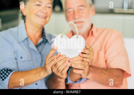 Amour saint valentin fête concept avec ancien senior couple en tenant un coeur blanc - ensemble famille d'intérieur et de relation à la maison avec matu Banque D'Images