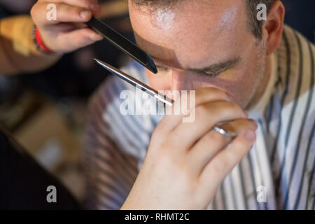 Heureux guy se coupe et les sourcils taillés par coiffure Banque D'Images