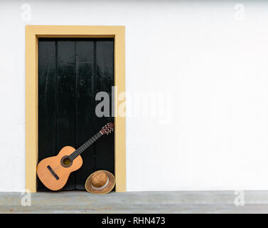 L'espagnol ou la guitare classique reposant sur une porte d'un patio andalou, copie espace droit. Une scène, un instrument de musique dans la région de mur blanc de la maison rurale Banque D'Images