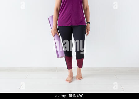 Yoga, personnes concept - Close up of woman holding mat après une classe de yoga sur fond blanc Banque D'Images