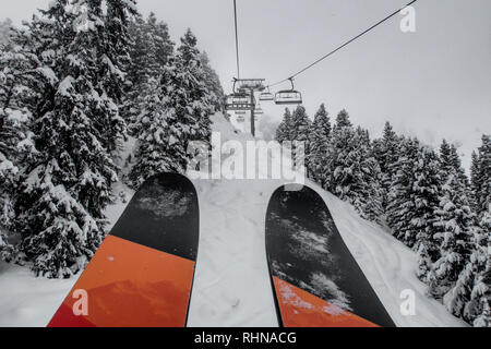 Télésiège de ski skieurs et planchistes portant jusqu'à la montagne pendant les fortes chutes de neige sur une journée d'hiver brumeux à Courchevel, France. Banque D'Images