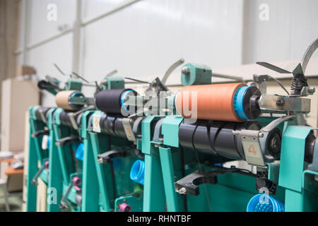 Groupe des cônes de canette sur une machine de gauchissement dans une usine de fabrication de fils textiles ball dans une usine textile. L'industrie textile - Une roue de bobines de fil Banque D'Images