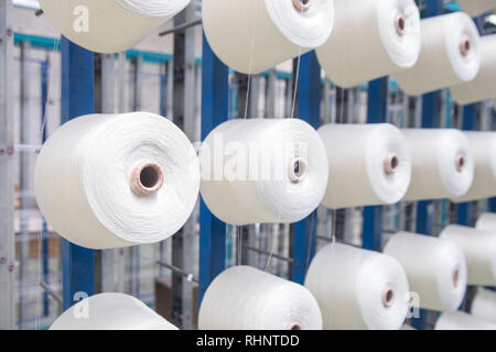 Groupe des cônes de canette sur une machine de gauchissement dans une usine de fabrication de fils textiles ball dans une usine textile. L'industrie textile - Une roue de bobines de fil Banque D'Images