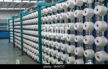 Groupe des cônes de canette sur une machine de gauchissement dans une usine de fabrication de fils textiles ball dans une usine textile. L'industrie textile - Une roue de bobines de fil Banque D'Images