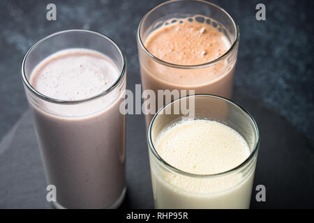 Des cocktails de protéines sur noir. La vanille, chocolat et fruits Boissons protéinées. La nutrition sportive. Banque D'Images