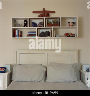 Simple étagère au-dessus de lit dans la chambre à coucher de style économique Banque D'Images