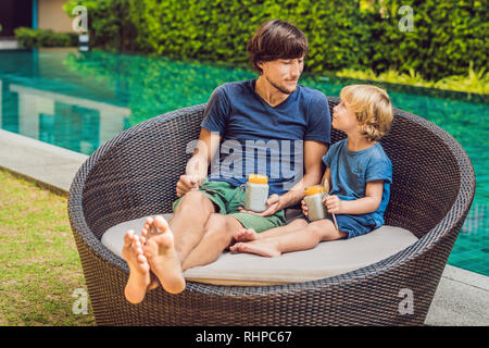 Père et fils manger le dessert avec chia seeds et de mangues à la piscine le matin. la saine alimentation, l'alimentation, les régimes végétariens et personnes concept Banque D'Images